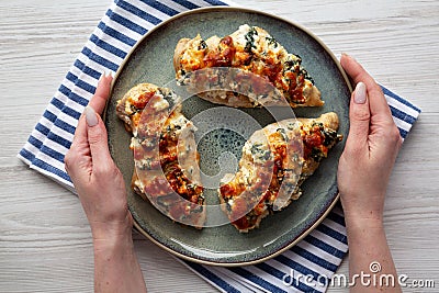 Female hands hold a plate with homemade Hasselback chicken, top view. Flat lay, overhead, from above Stock Photo
