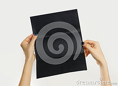 Female hands holding a black booklet triple sheet of paper. Isolated on gray background. Closeup Stock Photo