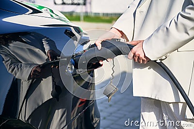 Female hands holding charger for electric car. Stock Photo