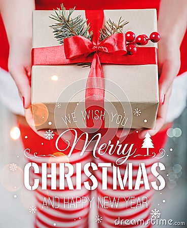 Female hands holding Christmas gift box with red ribbon and Merry Christmas and New Year typographical on shiny xmas background Stock Photo