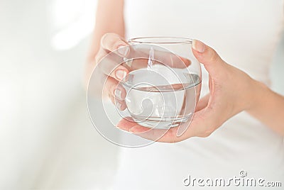 Female hands holding a clear glass of water.A glass of clean mineral water in hands, healthy drink. Stock Photo