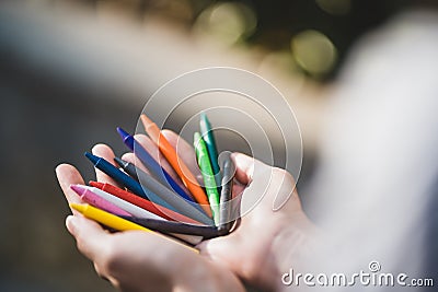 Female hands holding colorful pencils in the park. Bunch of multicolored crayons in hand Stock Photo