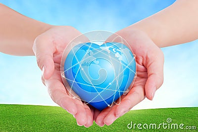 Female hands holding on earth global heart on grassland. Stock Photo