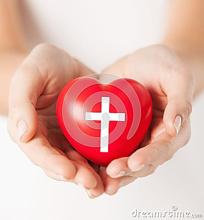 Female hands holding heart with cross symbol Stock Photo