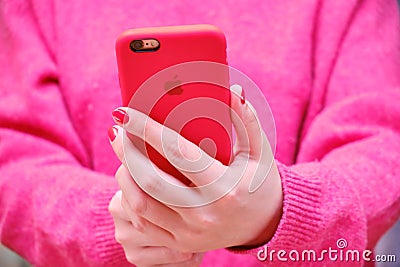 Female hands holding the iphone Apple in a red case. The girl holds the phone and takes a selfie photo Editorial Stock Photo