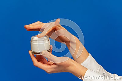 Female hands holding open cosmetic cream container Stock Photo