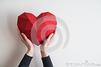 Female hands holding red polygonal heart shape Stock Photo