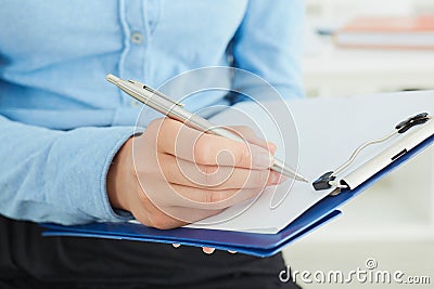 Female hands holding a silver pen closeup. Business woman making notes at office workplace. Stock Photo