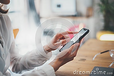 Female hands holding smartphone and touching screen.Businesswoman using mobile phone.Closeup on blurred background. Stock Photo