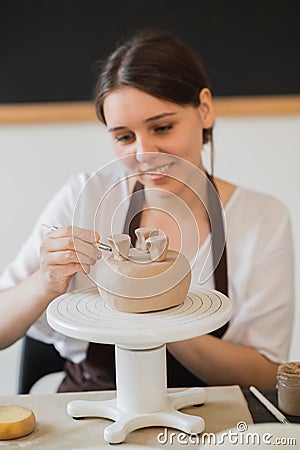 Female hands holding stick and making ornament on decorative product. Clay master moulding clay on a pottery and Stock Photo