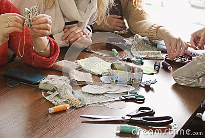 A group of women working and manufacturing brooch from fabric remnants, threads and shreds Stock Photo