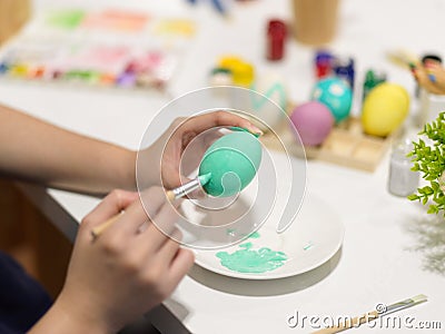 Female hands painting Easter eggs with poster colour on the table Stock Photo