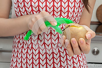 Female hands peel potatoes with a peeler Stock Photo