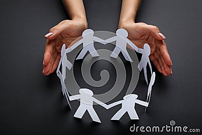Hands protecting paper chain people Stock Photo