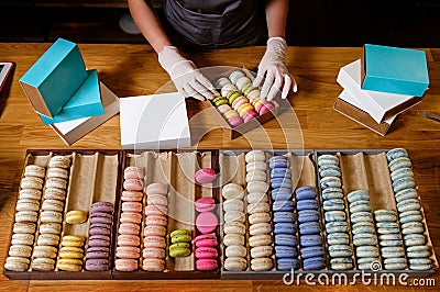 Female hands puts colorful macaroons in a paper box Stock Photo