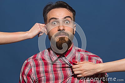 Female hands rumple young bearded handsome man on blue background Stock Photo