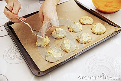 Female hands spread the cookie dough on a baking sheet covered with baking paper Stock Photo