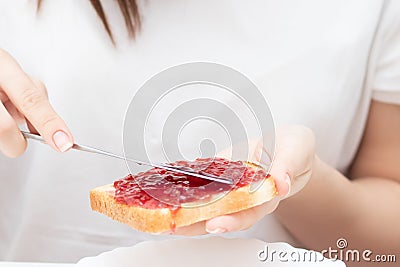 Female hands spread raspberry jam on bread, prepare sandwiches in the morning at home for breakfast for the whole family Stock Photo