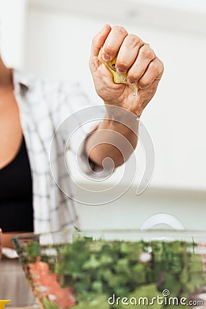 Female hands squeezing and adding lemon juice to vegetarian salad Stock Photo