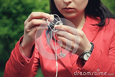 Female hands unravel the white little headphones outdoor Stock Photo