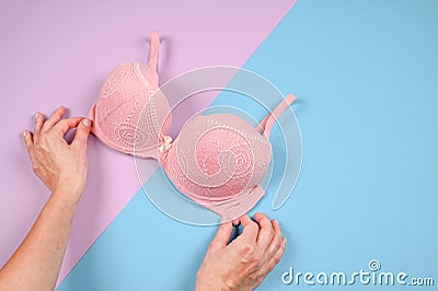 Female hands on a violetand blue background holding a beautiful pink bra. Daily underwear concept. Sales concept Stock Photo