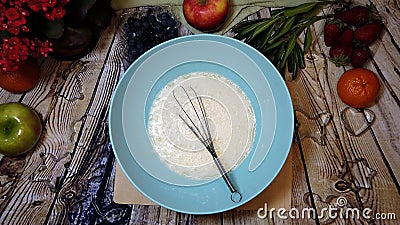 female hands whip eggs in bowl on the kitchen table by the window, top view Stock Photo