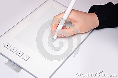 Female hands work on a graphic tablet. Hand holds stylus pen and draws. White graphic tablet. The work of a graphic designer. Girl Stock Photo