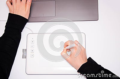 Female hands work on a graphic tablet. Hand holds stylus pen and draws. White graphic tablet. The work of a graphic designer. Girl Stock Photo