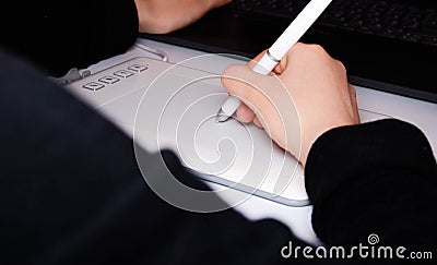 Female hands work on a graphic tablet. Hand holds stylus pen and draws. White graphic tablet. The work of a graphic designer. Girl Stock Photo