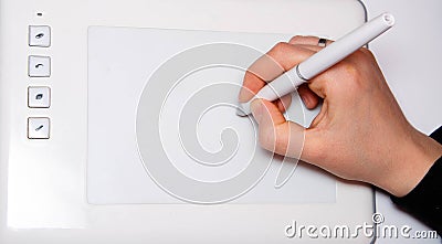 Female hands work on a graphic tablet. Hand holds stylus pen and draws. White graphic tablet. The work of a graphic designer. Girl Stock Photo