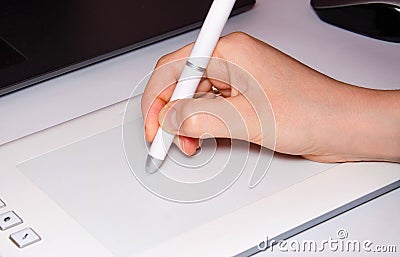 Female hands work on a graphic tablet. Hand holds stylus pen and draws. White graphic tablet. The work of a graphic designer. Girl Stock Photo