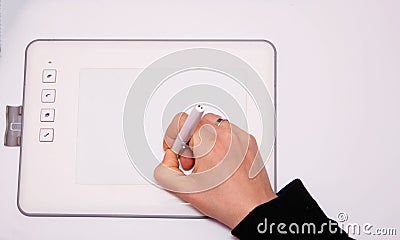 Female hands work on a graphic tablet. Hand holds stylus pen and draws. White graphic tablet. The work of a graphic designer. Girl Stock Photo