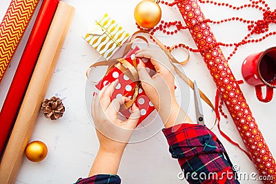 Female hands wrapping xmas gifts into paper and tying them up wi Stock Photo