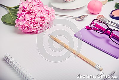 Top view Female working place with notebook for planning, cosmetic, sketchbook, glasses, and wisteria flowers on the white backgro Stock Photo