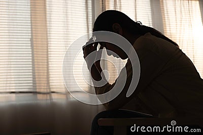 Female having depression sitting alone in bedroom dark corner. woman headache unhappy emotion. young anxiety despairing mental Stock Photo