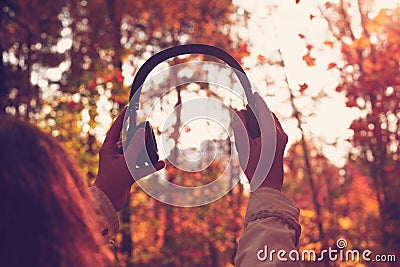 Female with headphones walking on the park listen sounds or music of autumn forest. Concept. Indian summer Stock Photo