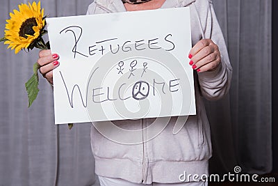Female helper welcomes refugees with sunflower Stock Photo