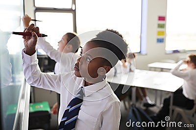 Female High School Students Wearing Uniform Using Interactive Whiteboard During Lesson Stock Photo