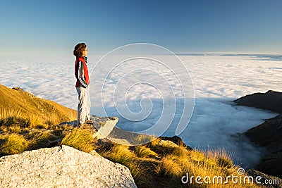 Female hiker reaching her goal at the mountain top and looking at majestic panoramic view of the italian western Alps with clouds Stock Photo