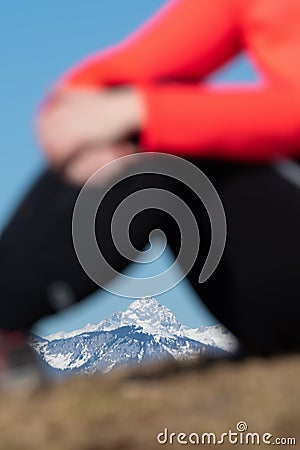 Female hiker sitting in foreground and framing snowcapped mountain in background Stock Photo