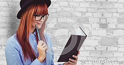 Female hipster reading book against wall Stock Photo