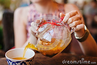 Female Hnds Pouring Sea Buckthorn Tea in Glass Kettle Stock Photo