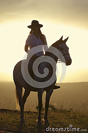 Female horseback rider and horse ride to overlook at Lewa Wildlife Conservancy in North Kenya, Africa at sunset Editorial Stock Photo