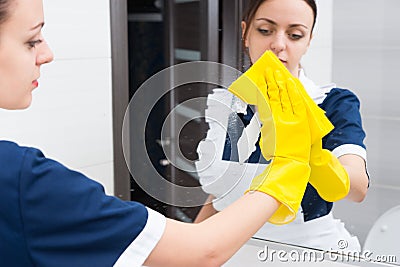Female hotel maid wiping bathroom mirror Stock Photo