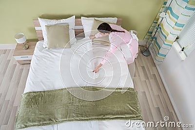 Female Housekeeper Arranging Bedsheet On Bed Stock Photo