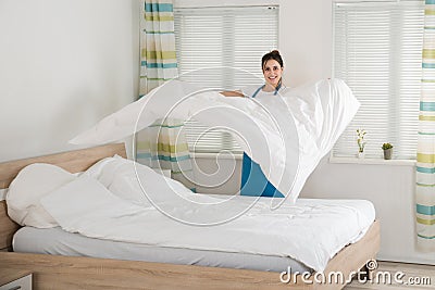 Female Housekeeper Changing Bedsheet On Bed Stock Photo