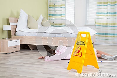 Female Housekeeper Unconscious Near Wet Floor Sign Stock Photo