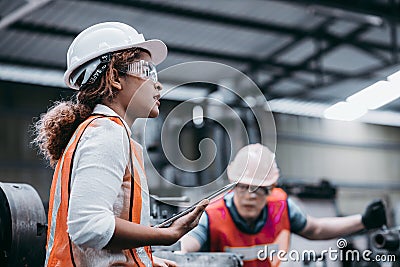 Female industrial engineer wearing a white helmet while Stock Photo