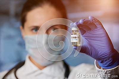 Female doctor holding in hand in disposable medical glove a coronavirus vaccine Stock Photo