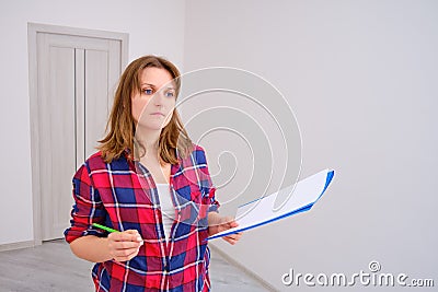 A female inspector in a plaid shirt inspects a new apartment in a built house Stock Photo